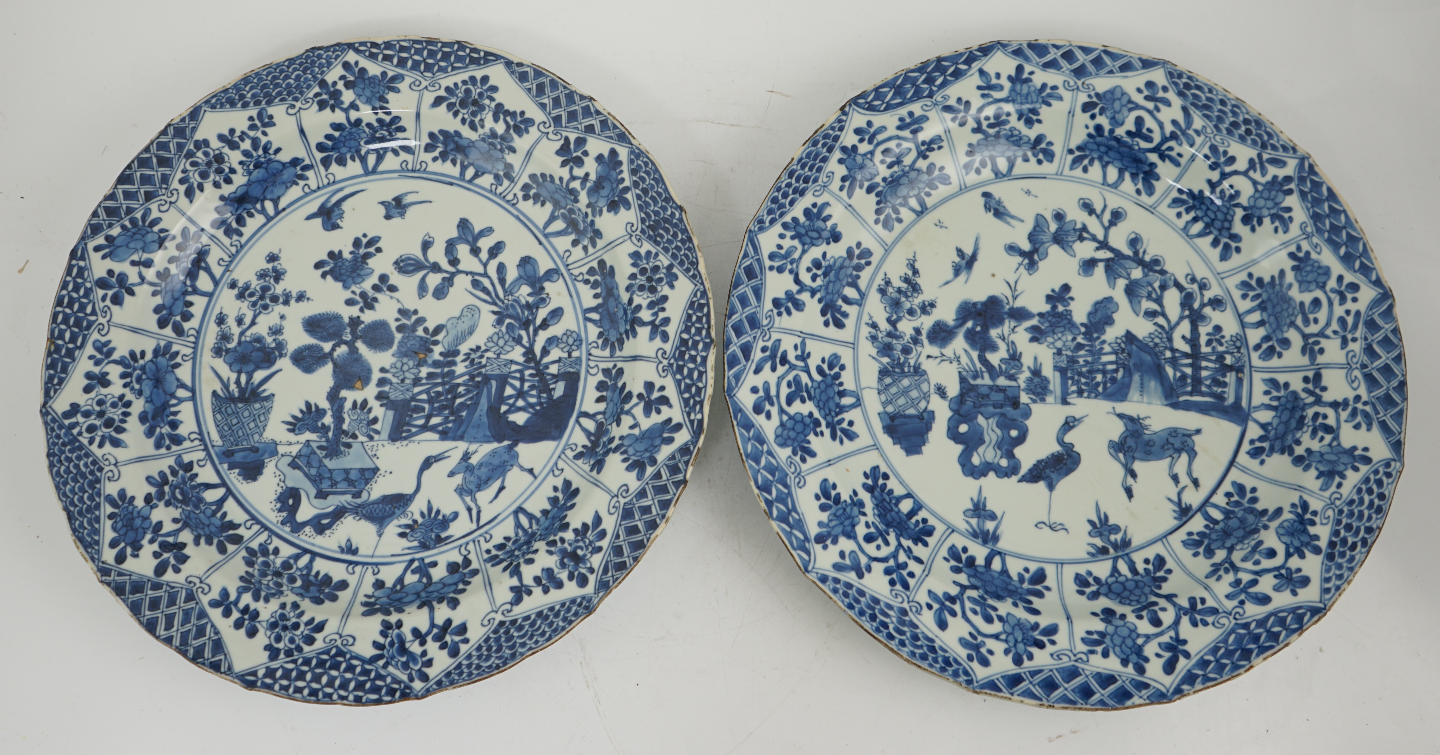 A pair of Chinese blue and white ‘garden’ dishes, Kangxi period, fritting and glaze chips